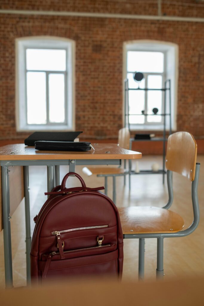 Spacious classroom setting with a backpack on a desk and chairs.